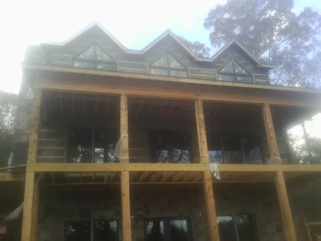 Dormers and porch framing on a large log home under construction — Roof Coating work by our crew in Hamshire