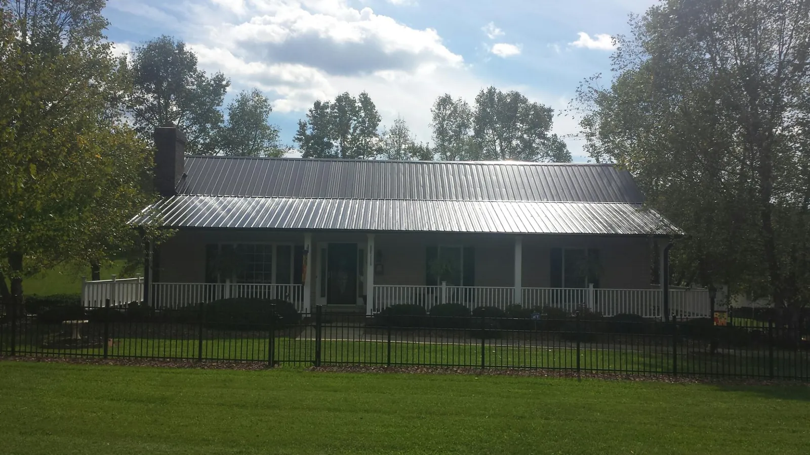 Gray metal roof on a brick ranch with a full width front porch — Gutter Guard Installation work by our crew in Hamshire