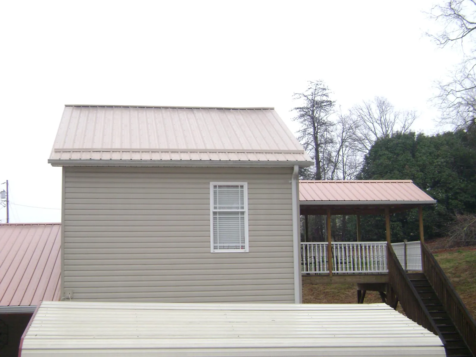 Tan metal roofs on a two story addition and attached porch, from a Roof Replacement job in Hamshire