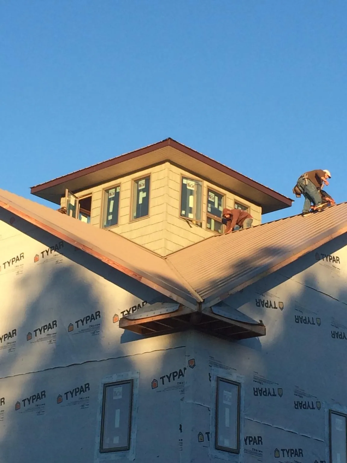 Roofers working around a rooftop cupola on a new metal roof at sunset — Roof Waterproofing in Hamshire by Roofing Brothers